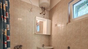 Un baño con bañera, inodoro, lavamanos y ventana.