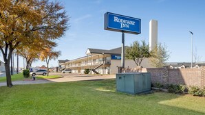 A hotel sign, a building, and a grassy area. - Rodeway Inn Garland Harbor Point (Garland)