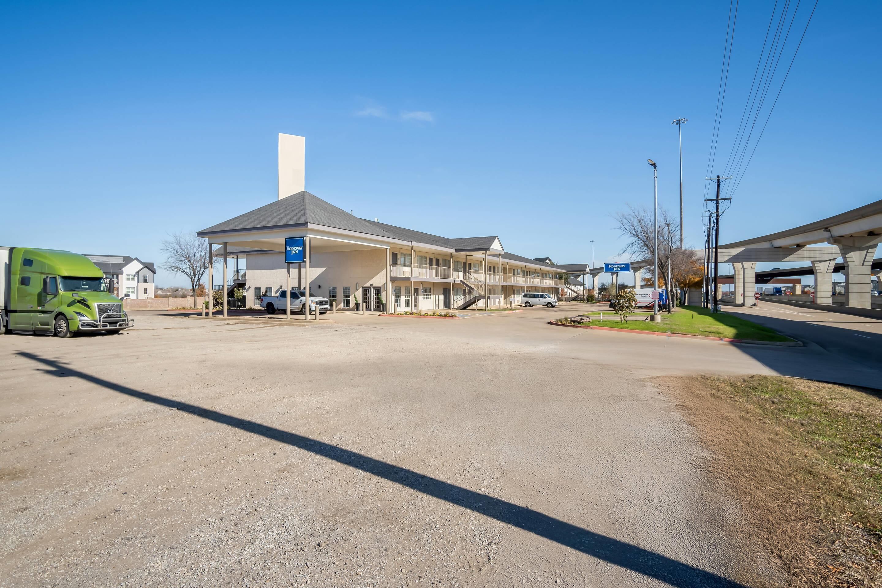 A gas station with a large building, a green truck, and a clear blue sky.
