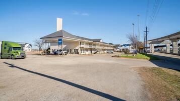A gas station with a large building, a green truck, and a clear blue sky.