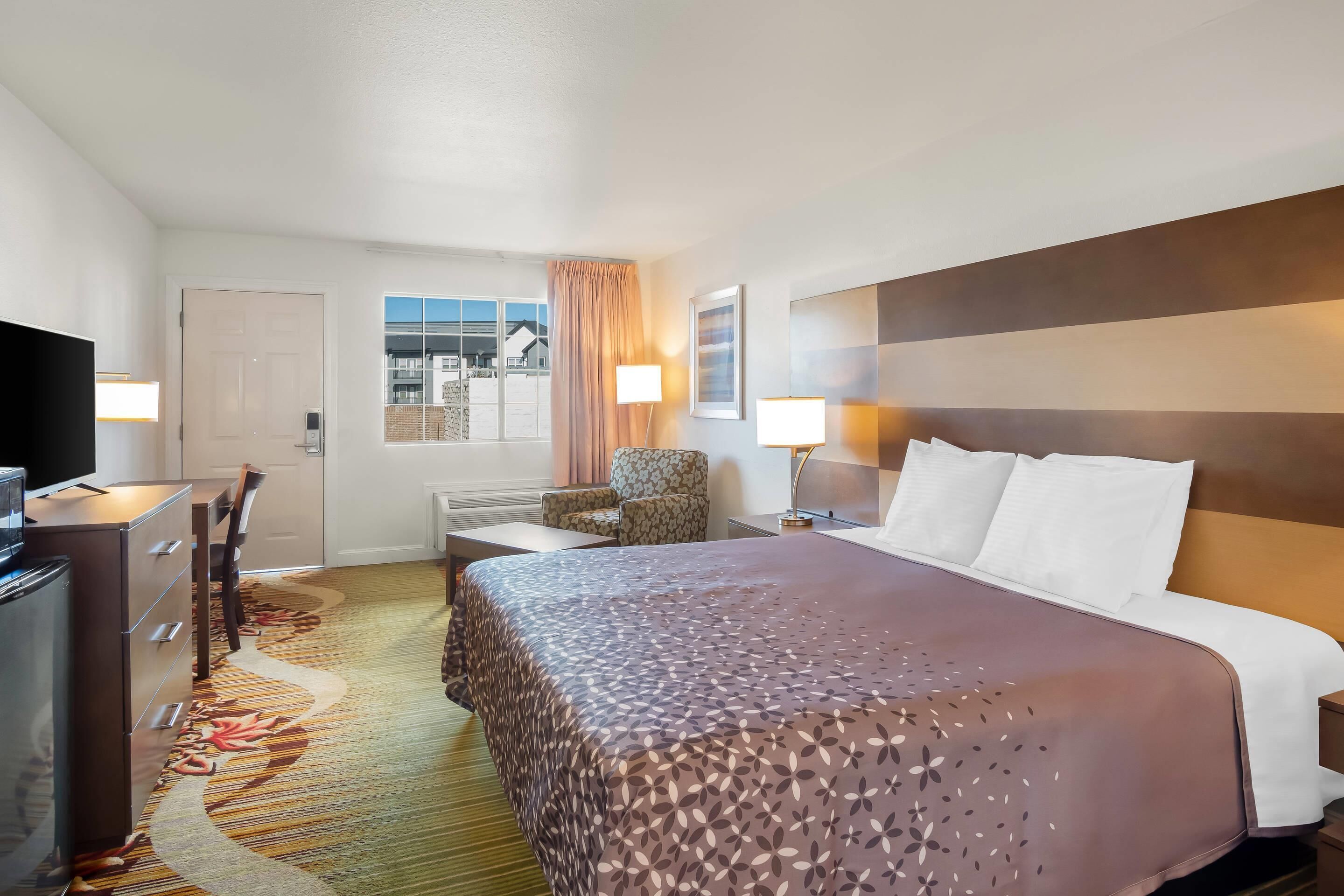 Una habitación de hotel con una cama, un escritorio, una silla y un televisor.