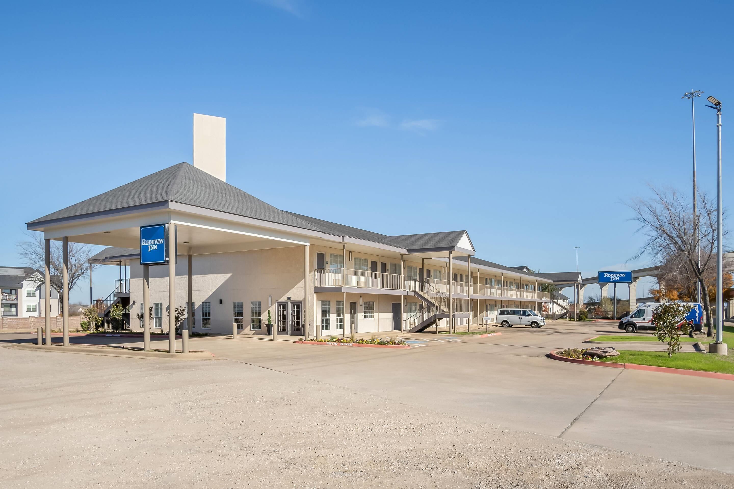 A motel with a covered parking area, a central staircase, and a sign indicating it is a Roadway Inn.