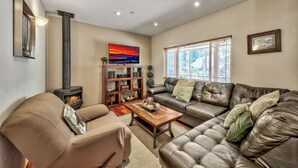 A cozy living room with a fireplace, leather sofa, and a bookshelf.
