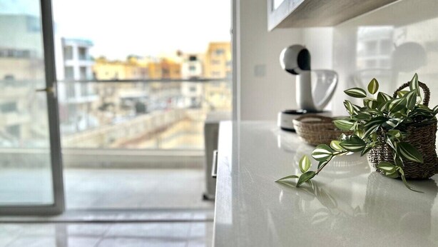 A modern kitchen with a large window, a white countertop, and a view of a cityscape.