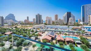 Un paysage urbain avec des immeubles modernes de grande hauteur, un vaste parking et une piscine entourée de verdure.