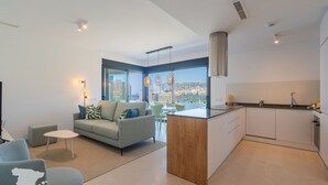 Un appartement moderne comprenant un salon, une cuisine et de grandes fenêtres donnant sur la ville.