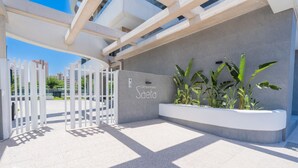 Une entrée moderne avec une façade en béton, un portail et un jardinier agrémenté de plantes vertes.