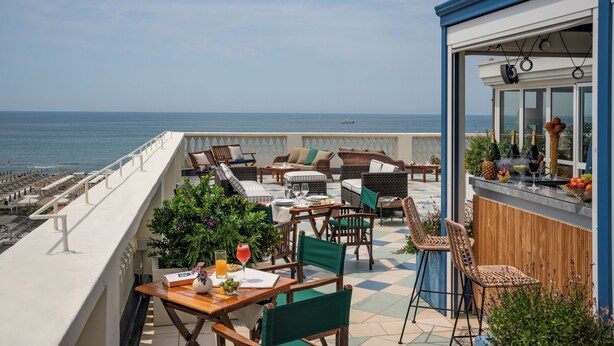 Een balkon met buitenmeubilair, een bar en uitzicht op zee.