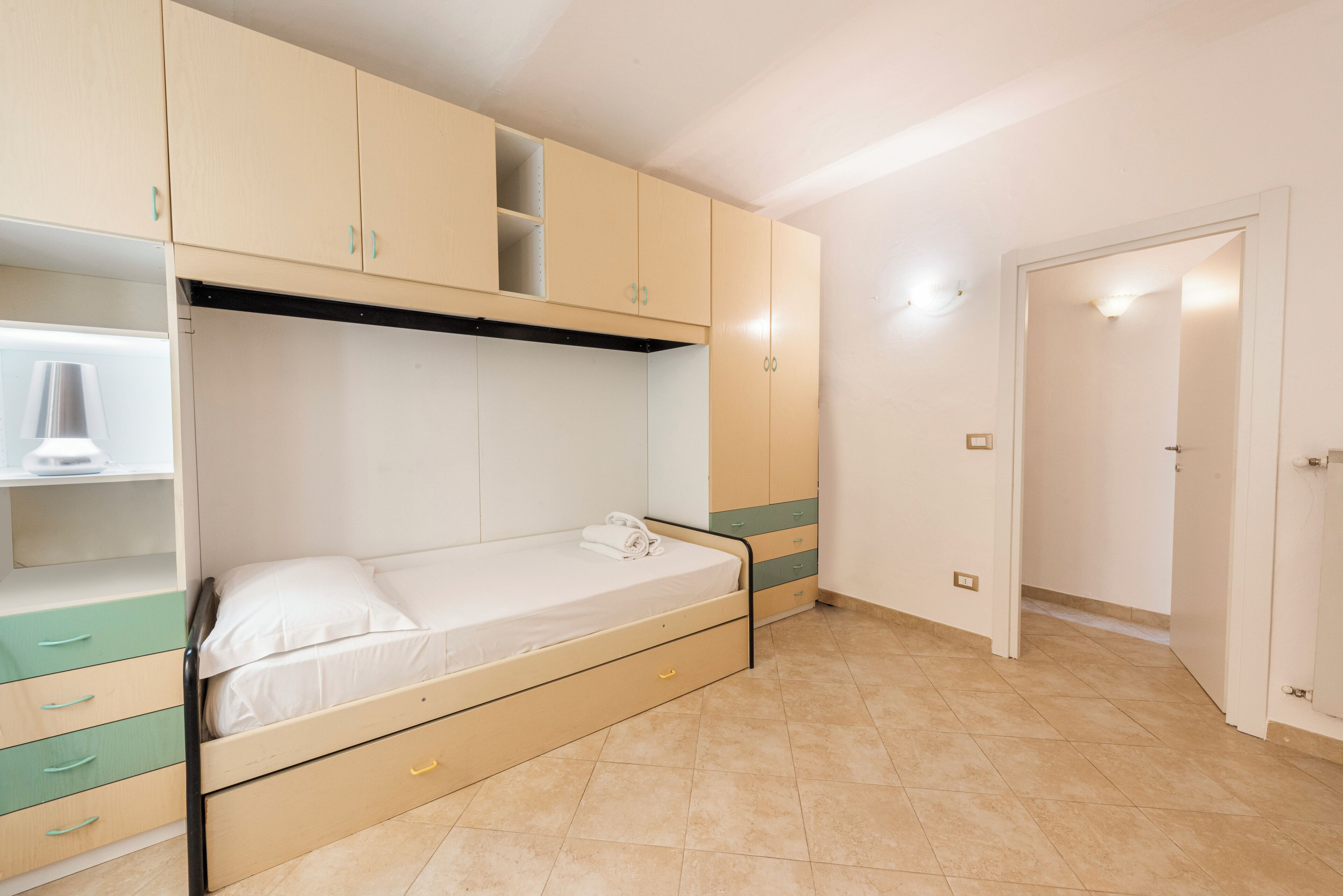 A bedroom with a bunk bed, built-in wardrobe, and a bedside table.
