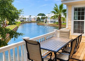 A deck with a table and chairs overlooking a water body with a dock and houses in the background. - 109 Georges Bay Road(Bermuda Bay) (Surfside Beach)