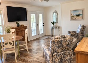 A living room with a wooden dining table, patterned armchairs, a television, and a large mirror. - 109 Georges Bay Road(Bermuda Bay) (Surfside Beach)