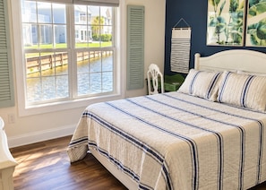 A bedroom with a large bed, a view of a water body outside, and a window with shutters. - 109 Georges Bay Road(Bermuda Bay) (Surfside Beach)