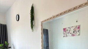 Ein Essbereich mit einem Holztisch, vier Stühlen, einer Blumenvase, einem großen Spiegel, einer Uhr und einer Zierpflanze.