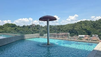 Relax by the serene pool surrounded by lush greenery and a stone deck.