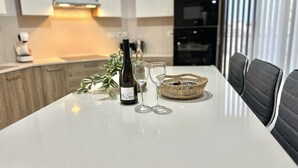 Eine moderne Küche mit weißer Arbeitsplatte, einer Weinflasche und einem Glas.