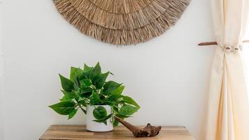 Um armário de madeira com padrão geométrico, um vaso com planta e um painel de parede tecido.