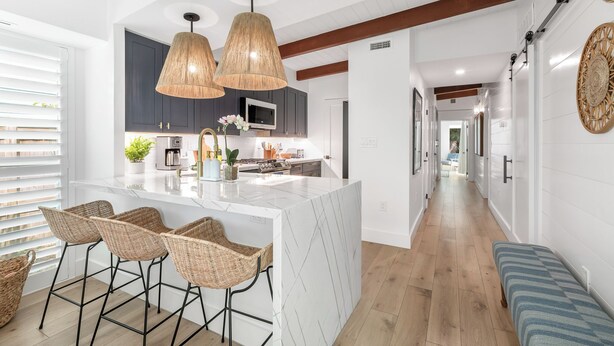 A modern kitchen with a central island, bar stools, and pendant lighting.