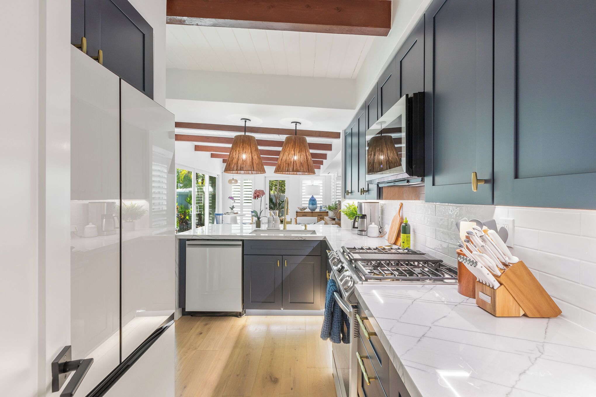 A modern kitchen with white cabinets, a central island, and pendant lighting.