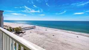 Ein Strand mit einem Steg, blauem Himmel und ruhiger See.