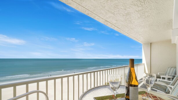 Ein Balkon mit Tisch für zwei Personen mit Blick auf einen Strand.