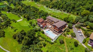An aerial view of a large, multi-story house with a swimming pool, surrounded by lush greenery and a golf course. - Residence Albatros A1 by Wonderful Italy (Toscolano Maderno)