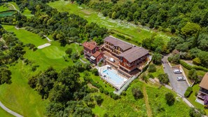 An aerial view of a large, multi-story house with a swimming pool, surrounded by lush greenery and a golf course. - Residence Albatros A1 by Wonderful Italy (Toscolano Maderno)