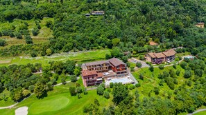 An aerial view of a large, multi-story building with a swimming pool, surrounded by lush greenery and a golf course. - Residence Albatros A1 by Wonderful Italy (Toscolano Maderno)