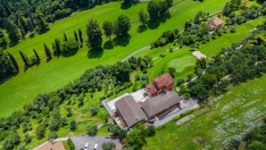 Vista aérea de una propiedad con un edificio central, campos verdes circundantes y un campo de golf.