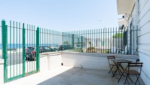 A balcony with a green metal fence, a table, and two chairs. - The Sea Outside Apartment 01 by Wonderful Italy (Bari)