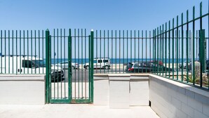 A gated parking area with vehicles, a clear sky, and a beach in the background. - The Sea Outside Apartment 01 by Wonderful Italy (Bari)