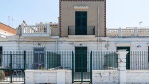 A building with a white facade, green shutters, and a balcony with a white balustrade. - The Sea Outside Apartment 01 by Wonderful Italy (Bari)