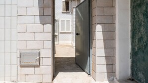 A narrow corridor with a closed door, a small window, and a utility box on the left wall. - The Sea Outside Apartment 02 by Wonderful Italy (Bari)