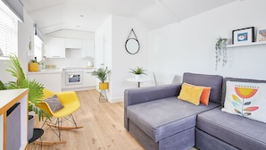 A modern living room with a grey sofa, yellow chair, and a small dining area. - Host Stay Sunnyside Studio (Bridlington)