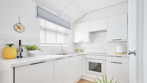A modern kitchen with white cabinets, a stainless steel sink, and a built-in oven. - Host Stay Sunnyside Studio (Bridlington)
