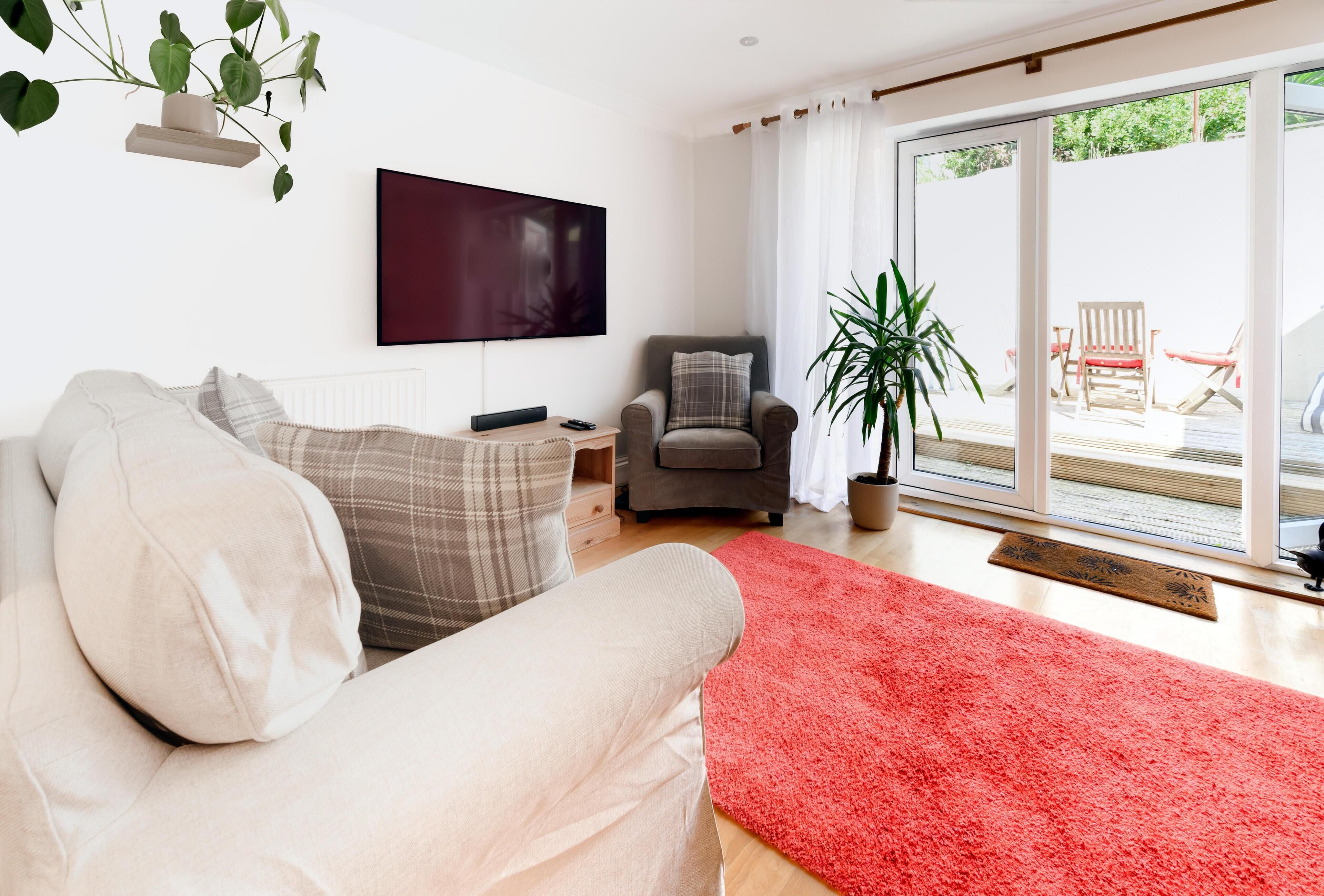 Un salon avec un canapé, un fauteuil, un téléviseur et une grande fenêtre.