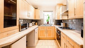 Eine moderne Küche mit Holzausstattung, integriertem Backofen, Spüle und Herd.