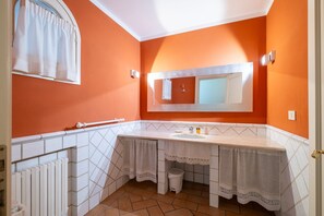 A bathroom with an orange wall, a white sink, and a mirror above it. - Casa Petroni in Bologna (Bologna)