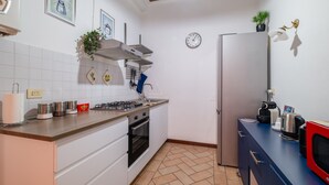 A modern kitchen with white cabinets, a gas stove, and a stainless steel refrigerator. - Casa Petroni in Bologna (Bologna)