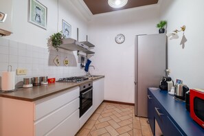 Una cocina moderna con armarios blancos, estufa a gas y refrigerador de acero inoxidable.