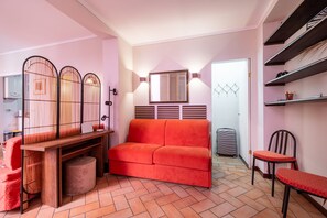 A compact living space with a sofa, a wooden desk, a chair, and a small table. - Casa Petroni in Bologna (Bologna)