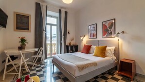 A hotel room with a bed, a desk, a chair, and a small table. - Rampa Brancaleone Charming Apartment With View (Rome)
