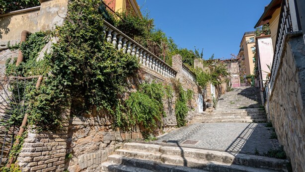 A stone staircase leading up a hill, surrounded by greenery and buildings. - Rampa Brancaleone Charming Apartment With View (Rome)
