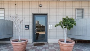 A building entrance with a door, two large potted plants, and a tiled floor. - Cloud Swing Apartment by Wonderful Italy (Bari)
