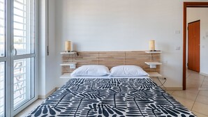A bedroom with a bed, a window, a wooden headboard, and a door. - Cloud Swing Apartment by Wonderful Italy (Bari)