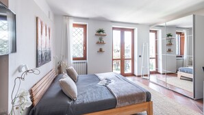 Une chambre à coucher avec un lit, une fenêtre, une porte et un miroir.