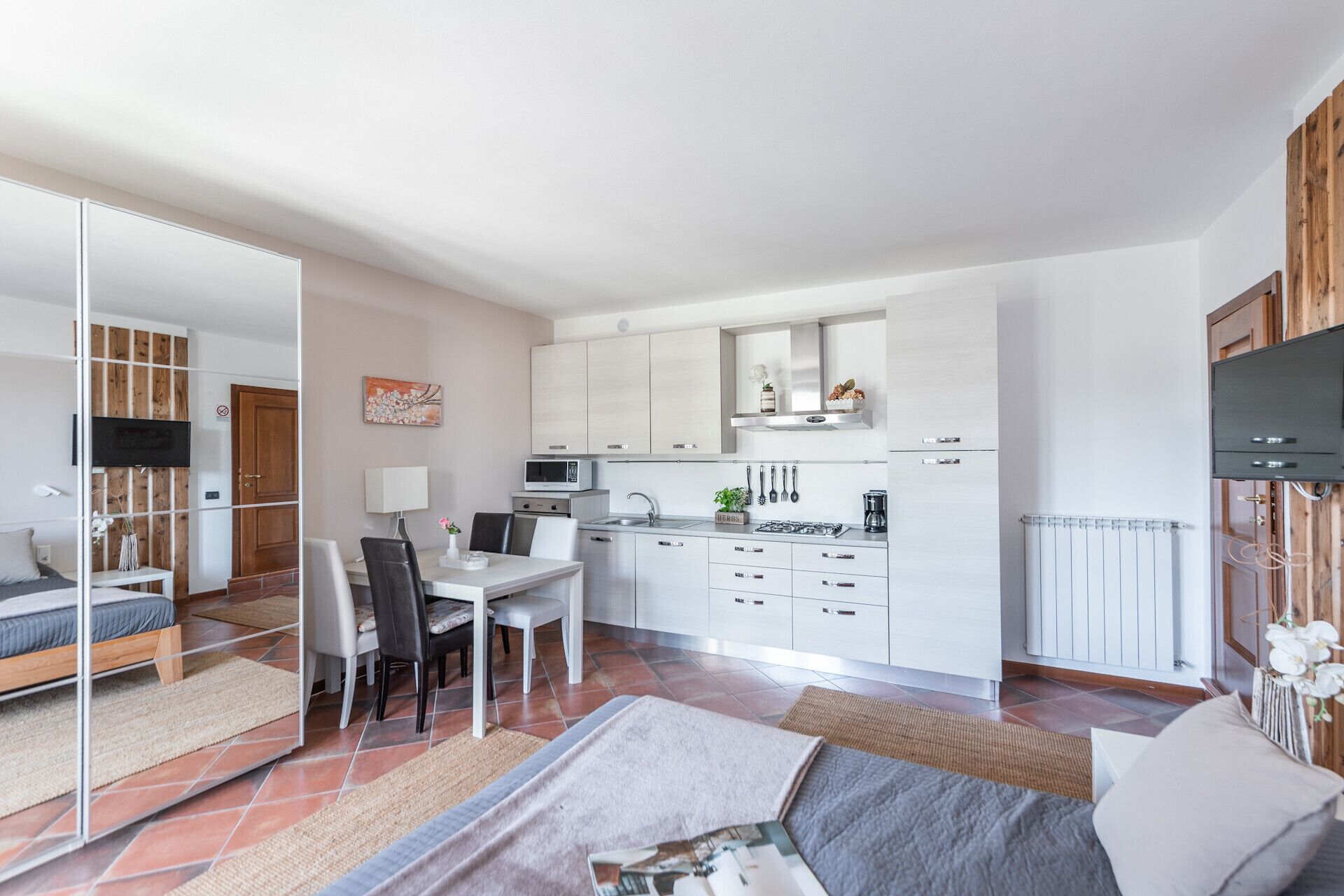Una habitación moderna y bien iluminada con cama, comedor y kitchenette.