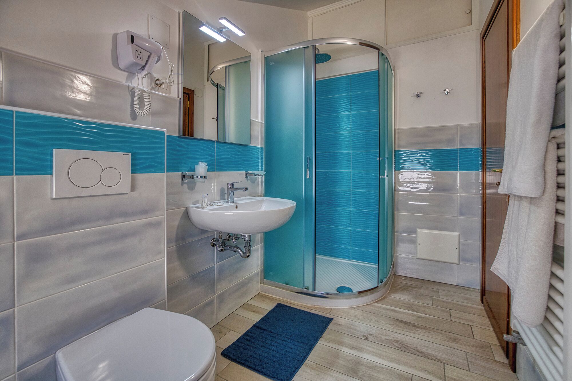 A bathroom with a white toilet, a sink, and a glass shower enclosure.