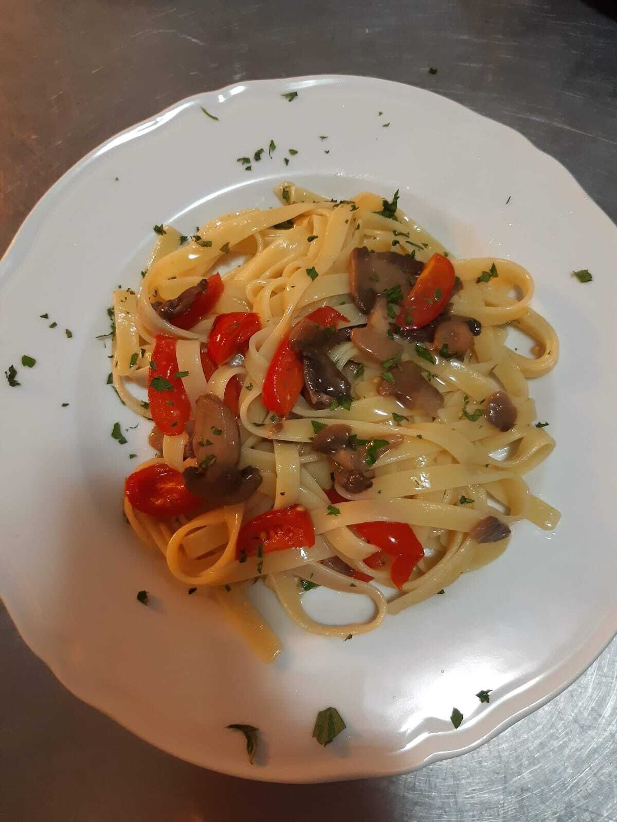 A plate of pasta with mushrooms and red peppers.