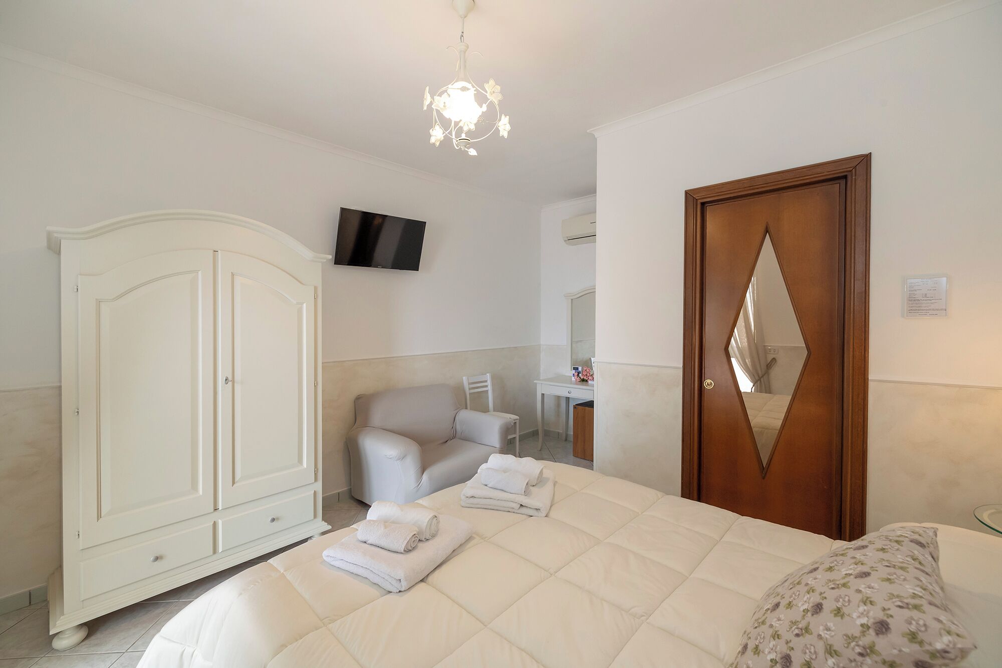 A bedroom with a bed, a wardrobe, a desk, a chair, and a mirror.