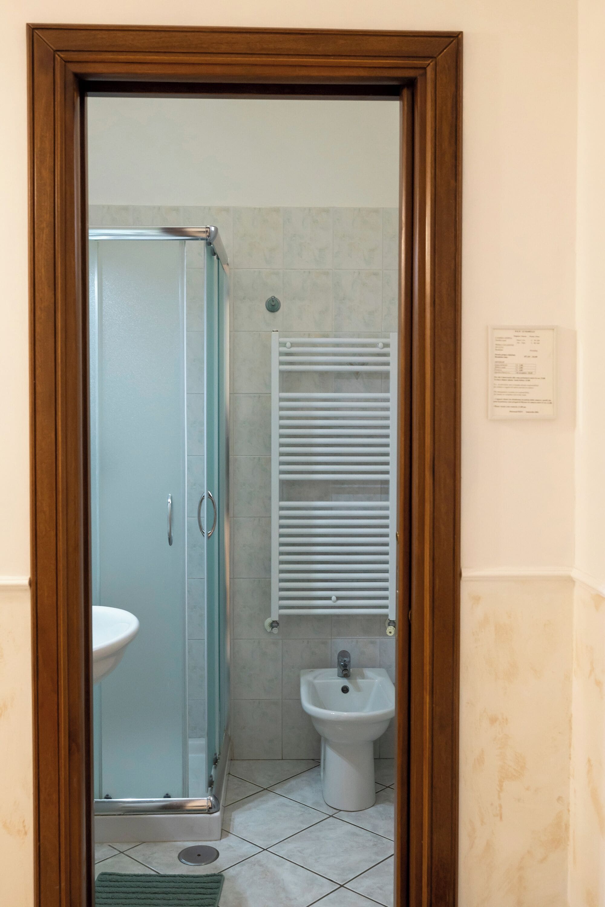 A bathroom with a glass-enclosed shower, a pedestal sink, and a wall-mounted towel rack.
